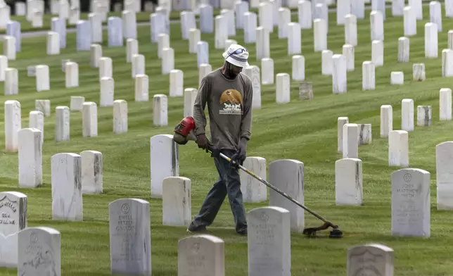 Todd Robinson trims along the rows of headstones at the Marietta National Cemetery located at 500 Washington Ave NE in Marietta, Ga., Thursday, May 23, 2024, in preparation for Memorial Day weekend. (John Spink/Atlanta Journal-Constitution via AP)
