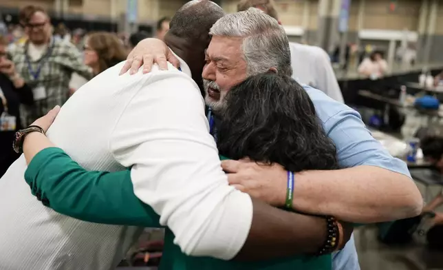 FILE - David Meredith, middle, hugs fellow observers after an approval vote at the United Methodist Church General Conference Wednesday, May 1, 2024, in Charlotte, N.C. When the United Methodist Church removed anti-LGBTQ language from its official rules in recent days, it marked the end of a half-century of debates over LGBTQ inclusion in mainline Protestant denominations. The moves sparked joy from progressive delegates, but the UMC faces many of the same challenges as Lutheran, Presbyterian and Episcopal denominations that took similar routes, from schisms to friction with international churches to the long-term aging and shrinking of their memberships. (AP Photo/Chris Carlson, File)