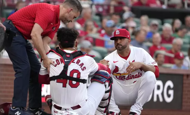 St. Louis Cardinals catcher Willson Contreras (40) is helped up by manager Oliver Marmol, right, and trainer Adam Olsen, left, after being injured during the second inning of a baseball game against the New York Mets Tuesday, May 7, 2024, in St. Louis. Contreras left the game. (AP Photo/Jeff Roberson)