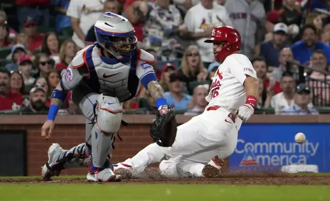 St. Louis Cardinals' Paul Goldschmidt, right, scores past New York Mets catcher Tomas Nido during the sixth inning of a baseball game Monday, May 6, 2024, in St. Louis. (AP Photo/Jeff Roberson)