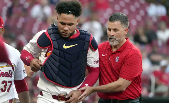 St. Louis Cardinals catcher Willson Contreras, left, is helped off the field by trainer Adam Olsen, right, after being injured during the second inning of a baseball game against the New York Mets Tuesday, May 7, 2024, in St. Louis. Contreras left the game. (AP Photo/Jeff Roberson)