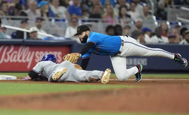 Miami Marlins third base Emmanuel Rivera, right, tags out New York Mets' Harrison Bader as he slides into third base during the fourth inning of a baseball game, Sunday, May 19, 2024, in Miami. (AP Photo/Wilfredo Lee)