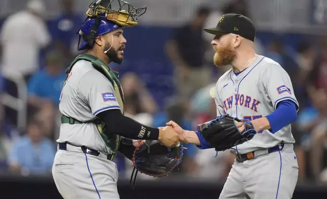 New York Mets relief pitcher Reed Garrett, right, and catcher Omar Narvaez celebrate after the Mets beat the Miami Marlins 7-3, during a baseball game, Sunday, May 19, 2024, in Miami. (AP Photo/Wilfredo Lee)