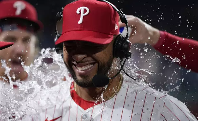 Philadelphia Phillies' Edmundo Sosa, center, is doused by Bryson Stott, left, and Brandon Marsh after the Phillies won a baseball game against the New York Mets, Wednesday, May 15, 2024, in Philadelphia. (AP Photo/Matt Slocum)