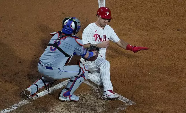 New York Mets catcher Tomas Nido, left, tags out Philadelphia Phillies' J.T. Realmuto at home after Realmuto tried to score on a two-run double by Bryce Harper during the fifth inning of a baseball game, Wednesday, May 15, 2024, in Philadelphia. (AP Photo/Matt Slocum)