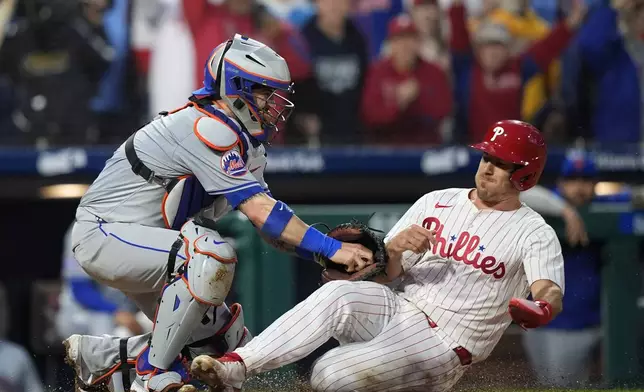 New York Mets catcher Tomas Nido, left, tags out Philadelphia Phillies' J.T. Realmuto at home after Realmuto tried to score on a two-run double by Bryce Harper during the fifth inning of a baseball game, Wednesday, May 15, 2024, in Philadelphia. (AP Photo/Matt Slocum)