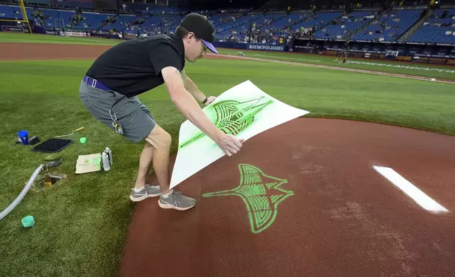 Tampa Bay Rays grounds crew member Cameron Merrick finishes painting the new City Connect logo on the back of the pitcher's mound before a baseball game against the New York Mets Friday, May 3, 2024, in St. Petersburg, Fla. (AP Photo/Chris O'Meara)