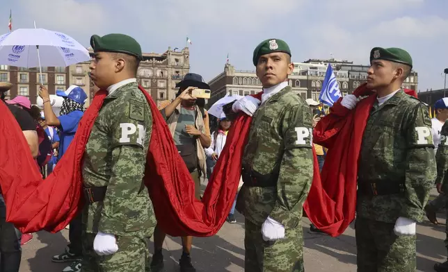 Members of Mexico's military hold the Mexican flag before an opposition rally at the Zocalo, Mexico City's main square, Sunday, May 19, 2024. (AP Photo/Ginnette Riquelme)