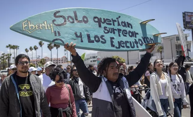 A demonstrator holding a bodyboard written in Spanish " They just wanted to surf and they were executed" protests the disappearance of foreign surfers in Ensenada, Mexico, Sunday, May 5, 2024. Mexican authorities said Friday that three bodies were recovered in an area of Baja California near where two Australians and an American went missing last weekend during an apparent camping and surfing trip. (AP Photo/Karen Castaneda)