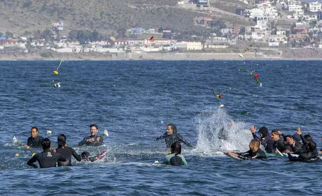 Surfers throw flowers during a tribute to 3 missing surfers in Ensenada, Mexico, Sunday, May 5, 2024. Mexican authorities said Friday that three bodies were recovered in an area of Baja California near where two Australians and an American went missing last weekend during an apparent camping and surfing trip. (AP Photo/Karen Castaneda)
