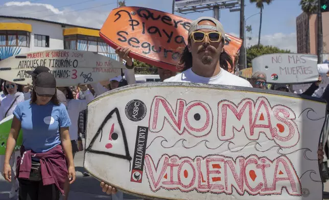 A demonstrator holding a bodyboard written in Spanish " No more violence" protests the disappearance of foreign surfers in Ensenada, Mexico, Sunday, May 5, 2024. Mexican authorities said Friday that three bodies were recovered in an area of Baja California near where two Australians and an American went missing last weekend during an apparent camping and surfing trip. (AP Photo/Karen Castaneda)