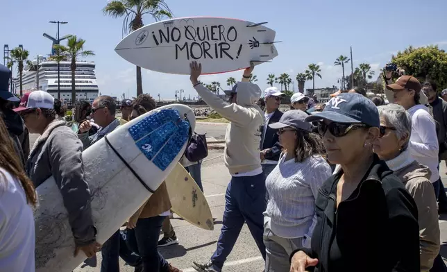 A demonstrator holding a bodyboard written in Spanish " I don't want to die" protests the disappearance of foreign surfers in Ensenada, Mexico, Sunday, May 5, 2024. Mexican authorities said Friday that three bodies were recovered in an area of Baja California near where two Australians and an American went missing last weekend during an apparent camping and surfing trip. (AP Photo/Karen Castaneda)