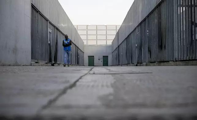 A volunteer walks in an open area of the Ponte Galeria center, one of the facilities created in Italy to detain migrants ahead of their repatriation, as they are considered ineligible for refugee status or international protection, in Rome, Tuesday, March 19, 2024. (AP Photo/Andrew Medichini)