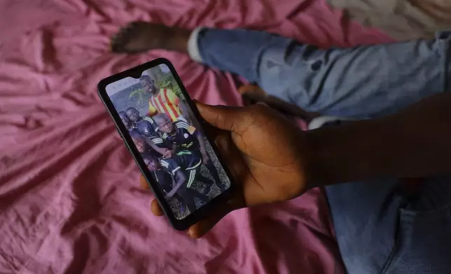 Allassane Sylla, younger brother of the late Ousmane Sylla, shows a photo of Ousmane, in a red and yellow shirt, on his phone in Matoto Bonagui, a suburb of Conakry, Guinea, Monday, April 8, 2024. (AP Photo/Misper Apawu)