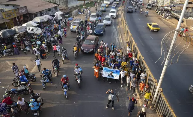 Family and friends march in the street to announce the funeral of the late Ousmane Sylla, ahead of the repatriation of his body in Conakry, Guinea, Monday, April 8, 2024. (AP Photo/Misper Apawu)