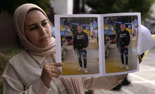 Dalia Elghaty, the aunt of a 27 year-old Egyptian, who he is accused of causing a shipwreck, holds photos of him outside a court house in Kalamata, southwestern Greece, on Tuesday, May 21, 2024. Nine Egyptian men have gone on trial in southern Greece, accused of causing a shipwreck that killed hundreds of migrants and sent shockwaves through the European Union's border protection and asylum operations. (AP Photo/Thanassis Stavrakis)