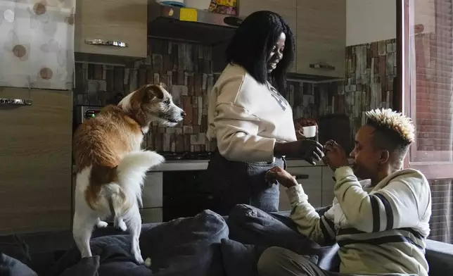 Ella Anthony, right , and her partner Doris Ezuruike Chinons, flanked by their dog Paddy, have a coffee during an interview in their house in Passo Corese, near Rome, Monday, March 11, 2024. Knowing that she faced a possible prison term since Nigeria criminalizes same-sex relationships, Anthony fled with her partner to Libya in 2014 and then Italy, where they both won asylum. Their claim? That they had a well-founded fear of anti-LGBTQ+ persecution back home. (AP Photo/Alessandra Tarantino)