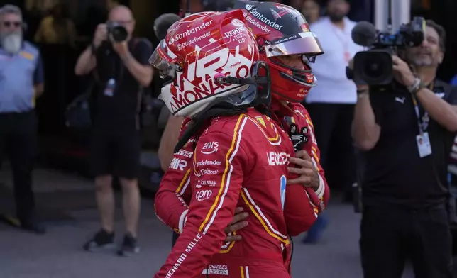 Ferrari driver Charles Leclerc of Monaco is congratulated by Ferrari driver Carlos Sainz of Spain, rear, after the qualifying session ahead of the Formula One Monaco Grand Prix at the Monaco racetrack, in Monaco, Saturday, May 25, 2024. (AP Photo/Luca Bruno)
