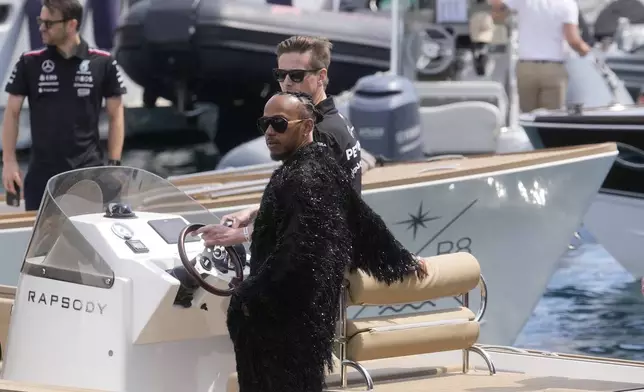 Mercedes driver Lewis Hamilton of Britain stands on a boat as he arrives in the paddock ahead of the first free practice at the Monaco racetrack, in Monaco, Friday, May 24, 2024. The Formula one race will be held on Sunday. (AP Photo/Luca Bruno)