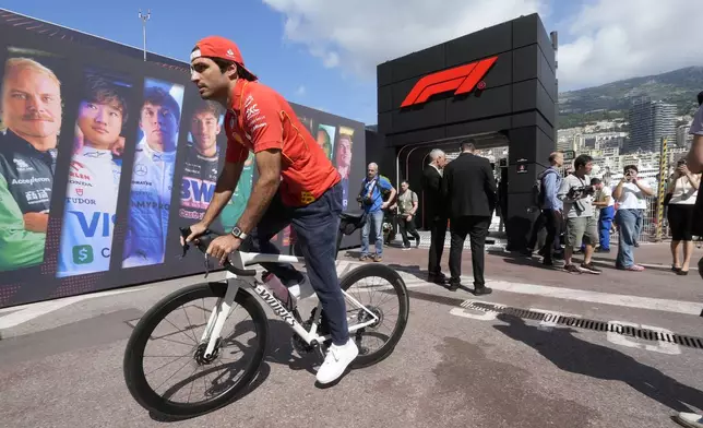 Ferrari driver Carlos Sainz of Spain bikes in the paddock ahead of the first free practice at the Monaco racetrack, in Monaco, Friday, May 24, 2024. The Formula one race will be held on Sunday. (AP Photo/Luca Bruno)