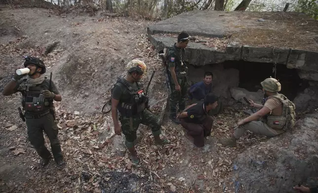 FILE - Members of the Karen National Liberation Army and People's Defense Force examine two arrested soldiers after they captured an army outpost, in the southern part of Myawaddy township in Kayin state, Myanmar, March 11, 2024. Six months into an offensive against Myanmar’s military administration, opposition forces have made massive gains, but civilian casualties are rising sharply as regime troops increasingly turn toward scorched-earth tactics in the Southeast Asian country's bitter civil war. (AP Photo/METRO, File)