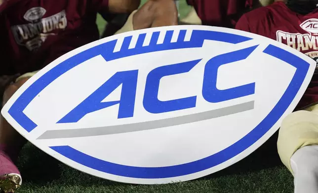 FILE - An Atlantic Coast Conference sign is displayed by Florida State players after the team's win over Louisville in the ACC championship NCAA college football game Dec. 2, 2023, in Charlotte, N.C. The NCAA and the nation's five biggest conferences have agreed to pay nearly $2.8 billion to settle a host of antitrust claims,a monumental decision that sets the stage for a groundbreaking revenue-sharing model that could start directing millions of dollars directly to athletes as soon as the 2025 fall semester. (AP Photo/Erik Verduzco, File)