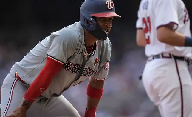 Washington Nationals outfielder Eddie Rosario (8) recoveres after stealing third base against the Atlanta Braves in the third inning of a baseball game, Monday, May 27, 2024, in Atlanta. (AP Photo/Mike Stewart)