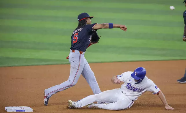 Washington Nationals shortstop CJ Abrams, left, turns a double play over a sliding Texas Rangers' Wyatt Langford, right, during the fourth inning of a baseball game in Arlington, Texas, Wednesday, May 1, 2024. Jonah Heim was out at first on the play. (AP Photo/Gareth Patterson)