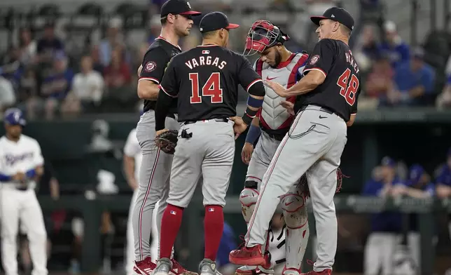 Washington Nationals pitching coach Jim Hickey (48) pays a mound visit to starting pitcher Mitchell Parker, Ildemaro Vargas (14) and catcher Keibert Ruiz, center rear, in the second inning of a baseball game against the Texas Rangers in Arlington, Texas, Thursday, May 2, 2024. (AP Photo/Tony Gutierrez)