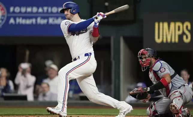 Texas Rangers' Jonah Heim follows through on an RBI single in the fourth inning of a baseball game against the Washington Nationals in Arlington, Texas, Tuesday, April 30, 2024. Nathaniel Lowe scored on the hit. (AP Photo/Tony Gutierrez)