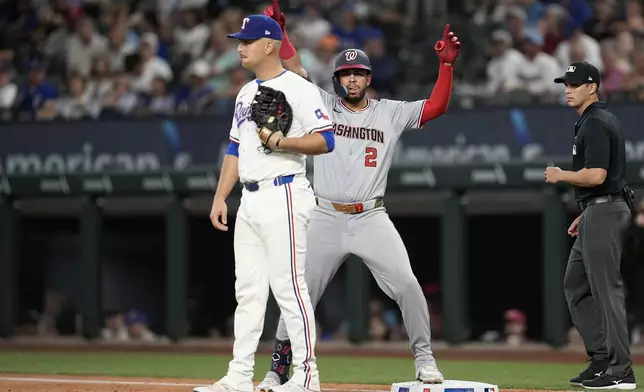 Washington Nationals' Luis Garcia Jr. (2) celebrates his RBI single behind Texas Rangers first baseman Nathaniel Lowe and umpire Edwin Jimenez, right, in the first inning of a baseball game in Arlington, Texas, Tuesday, April 30, 2024. CJ Abrams scored on the hit. (AP Photo/Tony Gutierrez)