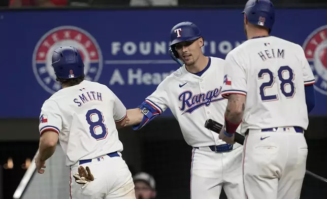 Texas Rangers' Josh Smith (8) and Jonah Heim (28) celebrate with Evan Carter, center, after scoring on an Travis Jankowski single in the eighth inning of a baseball game against the Washington Nationals in Arlington, Texas, Thursday, May 2, 2024. (AP Photo/Tony Gutierrez)