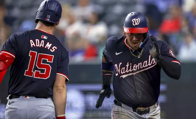 Washington Nationals' Ildemaro Vargas, right, runs to the dugout past Riley Adams (15) after Vargas scored on a single by Alex Call during the second inning of a baseball game against the Texas Rangers in Arlington, Texas, Wednesday, May 1, 2024. (AP Photo/Gareth Patterson)