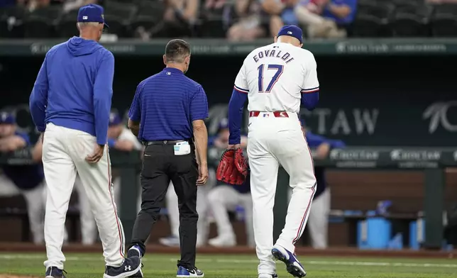 Texas Rangers starting pitcher Nathan Eovaldi (17) walks off the field with pitching coach Mike Maddux, left, and head athletic trainer Matt Lucero, center, during the sixth inning of a baseball game against the Washington Nationals in Arlington, Texas, Thursday, May 2, 2024. Eovaldi left the game with an unknown injury. (AP Photo/Tony Gutierrez)