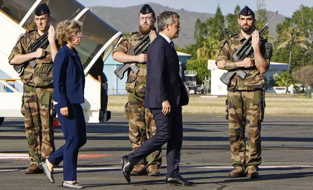France's Minister for Interior and Overseas Gerald Darmanin and French Minister for Overseas Marie Guevenoux walk past an honor guard on arrival at Noumea ñ La Tontouta International airport, in Noumea, New Caledonia, Thursday, May 23, 2024. French President Emmanuel Macron has landed in riot-hit New Caledonia, having crossed the globe by plane from Paris in a high-profile show of support for the French Pacific archipelago wracked by deadly unrest and where indigenous people have long sought independence from France. (Ludovic Marin/Pool Photo via AP)