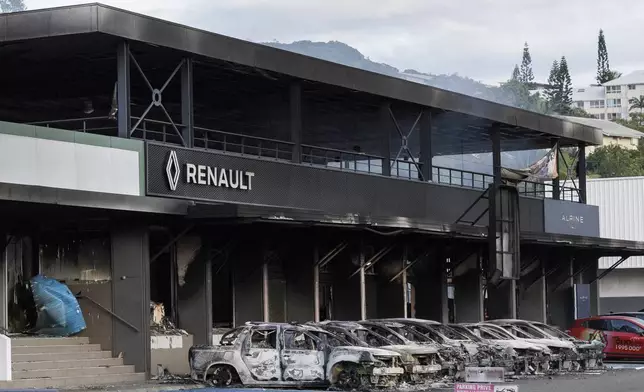 A burnt car store is pictured in Noumea, New Caledonia, Tuesday May, 14, 2024. France has imposed a state of emergency in the French Pacific territory of New Caledonia. The measures imposed on Wednesday for at least 12 days boost security forces' powers to quell deadly unrest that has left four people dead, erupting after protests over voting reforms. (AP Photo/Cedric Jacquot)