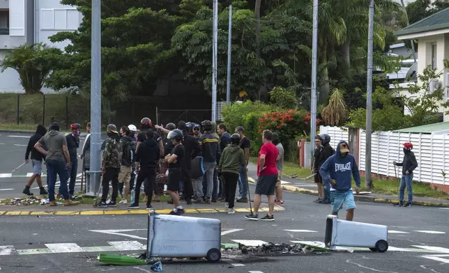 Residents gather in a street in Noumea, New Caledonia, Wednesday May 15, 2024. France has imposed a state of emergency in the French Pacific territory of New Caledonia. The measures imposed on Wednesday for at least 12 days boost security forces' powers to quell deadly unrest that has left four people dead, erupting after protests over voting reforms. (AP Photo/Nicolas Job)