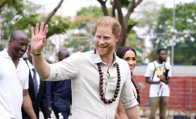 Prince Harry gestures as he and Meghan visit children at the Lights Academy in Abuja, Nigeria, Friday, May 10, 2024. Prince Harry and his wife Meghan have arrived in Nigeria to champion the Invictus Games, which he founded to aid the rehabilitation of wounded and sick servicemembers and veterans. (AP Photo/Sunday Alamba)