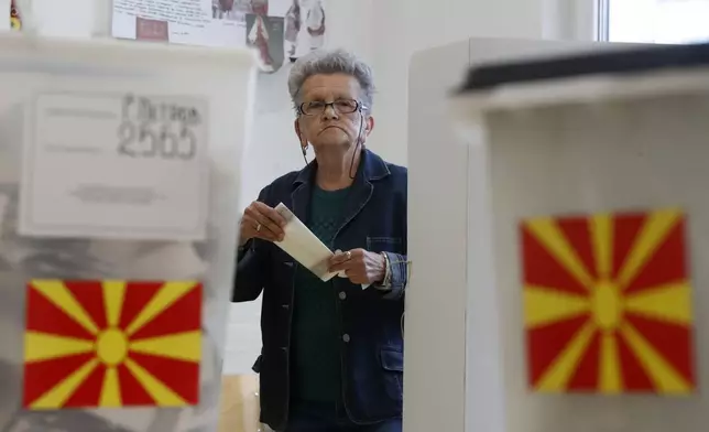 A woman casts her ballots during the parliamentary election and the presidential runoff, at a polling stationin Skopje, North Macedonia, on Wednesday, May 8, 2024. Voters in North Macedonia were casting ballots on Wednesday in a parliamentary election and a presidential runoff dominated by issues including the country's path toward European Union membership, corruption and the economy. (AP Photo/Boris Grdanoski)