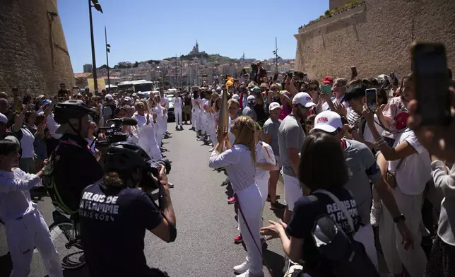 Karolina Pelendritou of Cyprus raises the flame during the Olympic torch relay in Marseille, southern France, Thursday, May 9, 2024. Torchbearers are to carry the Olympic flame through the streets of France' s southern port city of Marseille, one day after it arrived on a majestic three-mast ship for the welcoming ceremony. (AP Photo/Daniel Cole)