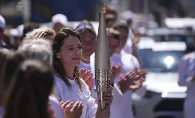 Ana Maria Branza of Romania participates in the Olympic torch relay in Marseille, southern France, Thursday, May 9, 2024. Torchbearers are to carry the Olympic flame through the streets of France' s southern port city of Marseille, one day after it arrived on a majestic three-mast ship for the welcoming ceremony. (AP Photo/Daniel Cole)