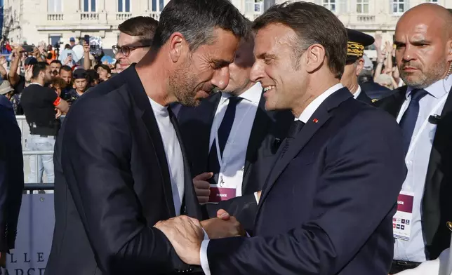 President of the Paris 2024 Olympics and Paralympics Organizing Committee Tony Estanguet, left, shakes hands French President Emmanuel Macron during the Olympic torch arrival ceremony in Marseille, southern France, Wednesday May 8, 2024. The Olympic flame arrived in Marseille's Old Port Wednesday on a majestic three-mast ship from Greece for the welcoming ceremony at sunset in the city's Old Port. (Ludovic Marin, Pool via AP)