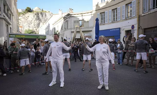 Torchbearers participate in the torch relay in Marseille, southern France, Thursday, May 9, 2024. Torchbearers are to carry the Olympic flame through the streets of France' s southern port city of Marseille, one day after it arrived on a majestic three-mast ship for the welcoming ceremony. (AP Photo/Laurent Cipriani)