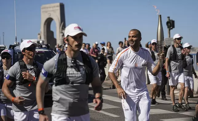 Former San Antonio Spurs guard Tony Parker participates in the torch relay in Marseille, southern France, Thursday, May 9, 2024. Torchbearers are to carry the Olympic flame through the streets of France' s southern port city of Marseille, one day after it arrived on a majestic three-mast ship for the welcoming ceremony. (AP Photo/Laurent Cipriani)