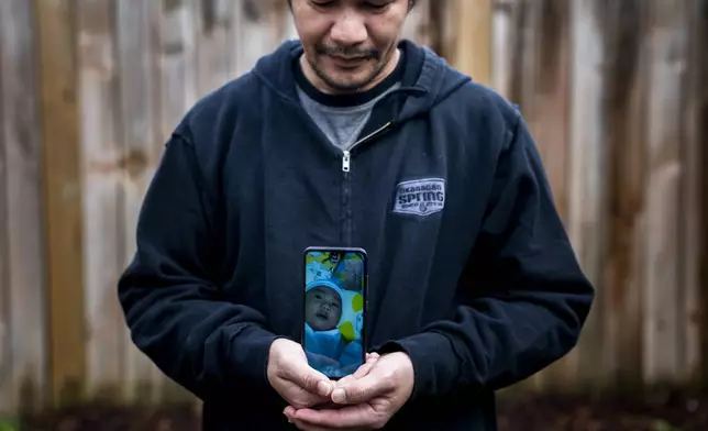 Seafarer Norberto Cabrela stands for a portrait while on a video call with his infant son, who he had not been able to meet in person, at a temporary rental house in Lacey, Wash., on Tuesday, Jan. 30, 2024. While waiting for backpay, stuck in the U.S., Cabrela missed the birth of his son, then scrambled to find the money to pay the hospital bills. (AP Photo/Lindsey Wasson)