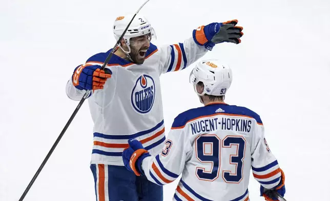 Edmonton Oilers' Evan Bouchard (2) and Ryan Nugent-Hopkins (93) celebrate after assisting on Zach Hyman's goal against the Vancouver Canucks during the second period in Game 7 of an NHL hockey Stanley Cup second-round playoff series in Vancouver, British Columbia, Monday, May 20, 2024. (Ethan Cairns/The Canadian Press via AP)