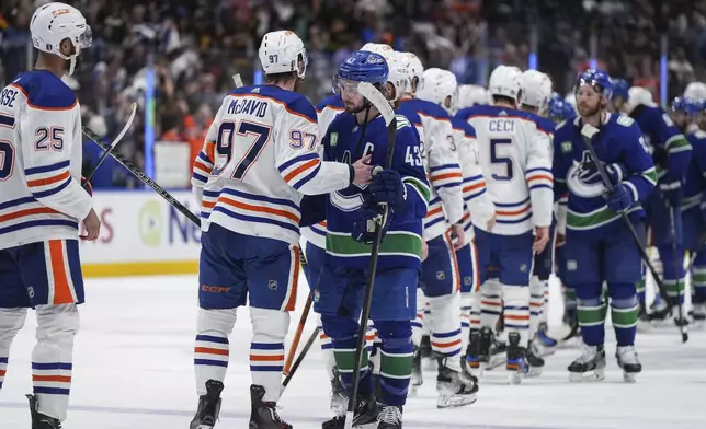 Vancouver Canucks' Quinn Hughes (43) and Edmonton Oilers' Connor McDavid (97) talk while shaking hands after Edmonton defeated Vancouver in Game 7 of an NHL hockey Stanley Cup second-round playoff series, in Vancouver, British Columbia, on Monday, May 20, 2024. (Darryl Dyck/The Canadian Press via AP)