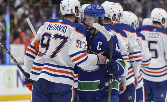 Vancouver Canucks' Quinn Hughes, front right, and Edmonton Oilers' Connor McDavid (97) talk after the Oilers won Game 7 of an NHL hockey Stanley Cup second-round playoff series in Vancouver, British Columbia, Monday, May 20, 2024. (Darryl Dyck/The Canadian Press via AP)