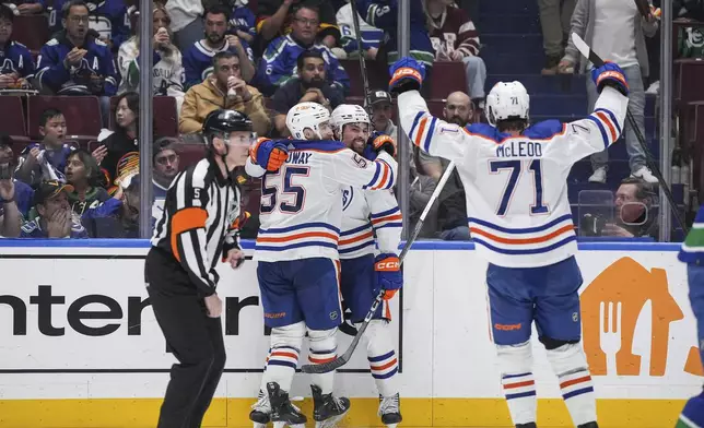 Edmonton Oilers' Dylan Holloway, center left, Cody Ceci, center right, and Ryan McLeod (71) celebrate after Ceci's goal against the Vancouver Canucks during the second period in Game 7 of an NHL hockey Stanley Cup second-round playoff series in Vancouver, British Columbia, Monday, May 20, 2024. (Darryl Dyck/The Canadian Press via AP)