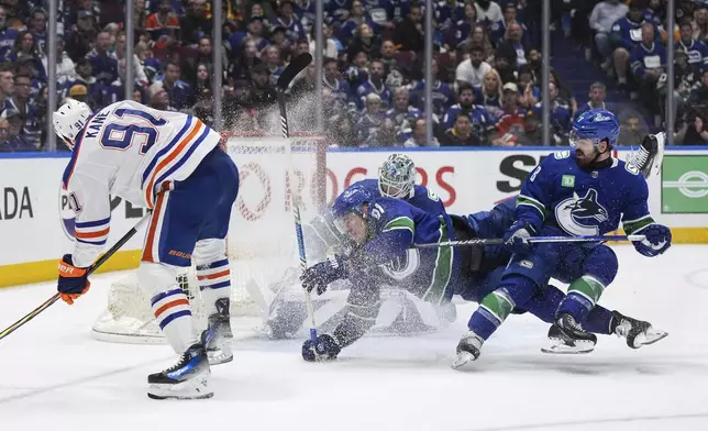 Vancouver Canucks' Conor Garland, right, and Nikita Zadorov, center front, collide after Canucks goalie Arturs Silovs, center back, stopped Edmonton Oilers' Evander Kane, left, during the second period in Game 7 of an NHL hockey Stanley Cup second-round playoff series in Vancouver, British Columbia, Monday, May 20, 2024. (Darryl Dyck/The Canadian Press via AP)